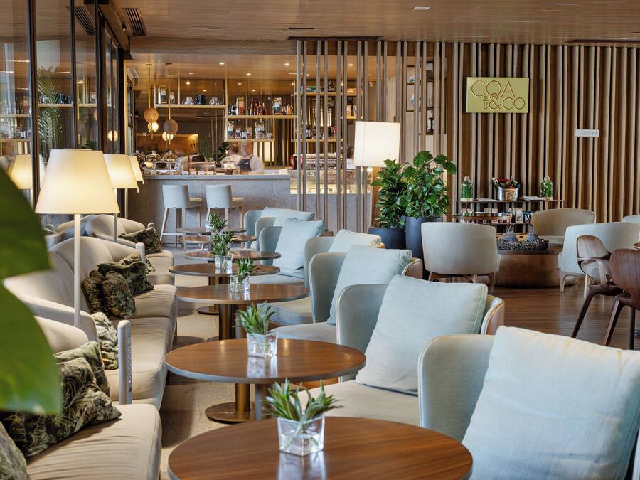 A modern hotel lobby with seating areas, a bar, and a reception desk.
