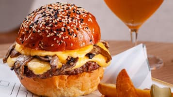 A meal consisting of a burger, fries, and a glass of beer on a plate.