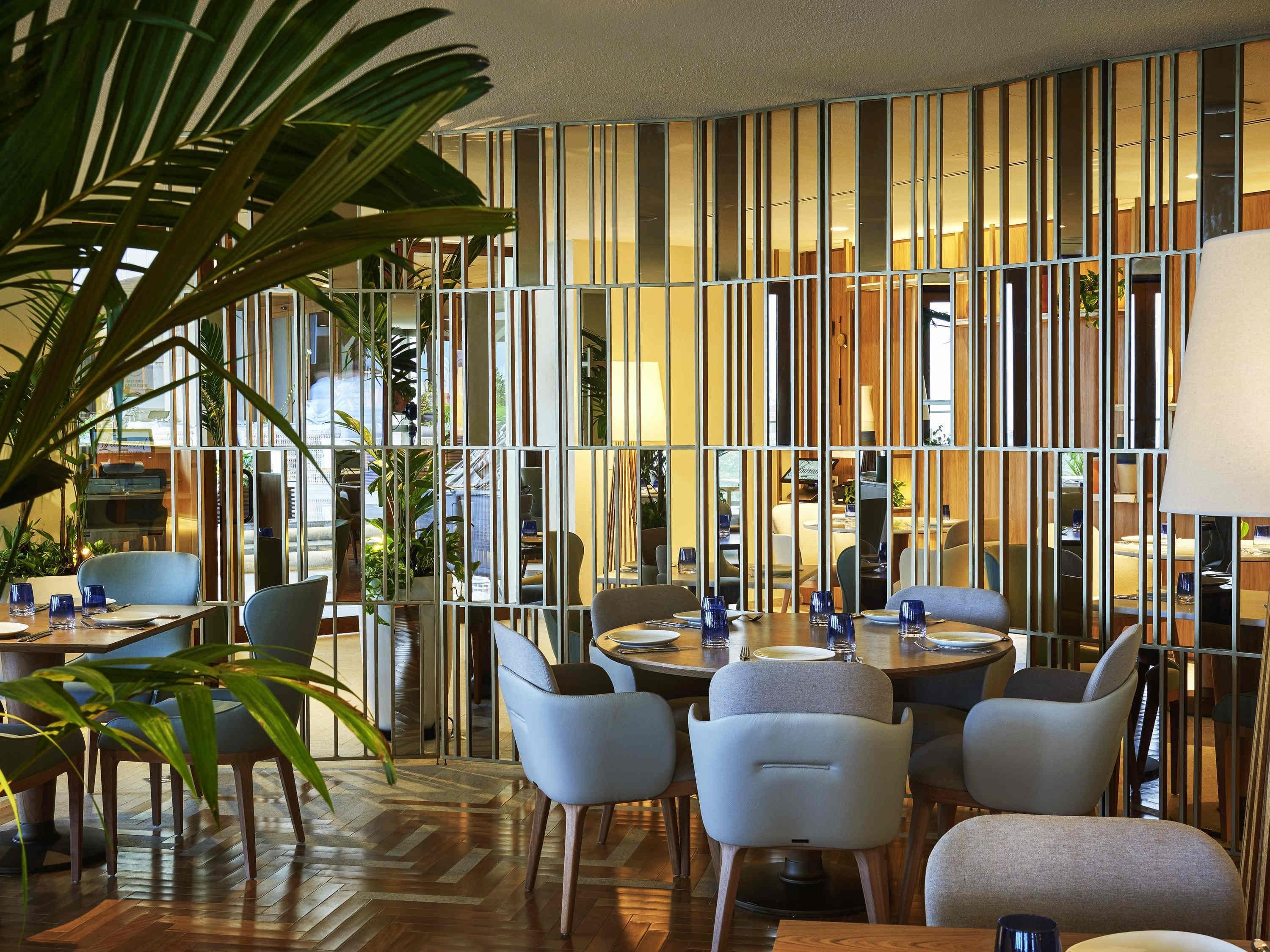 A modern dining area with a wooden floor, striped partition wall, and comfortable seating.
