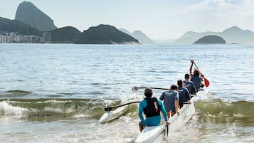 A group of people rowing in a boat on a body of water with mountains in the background.