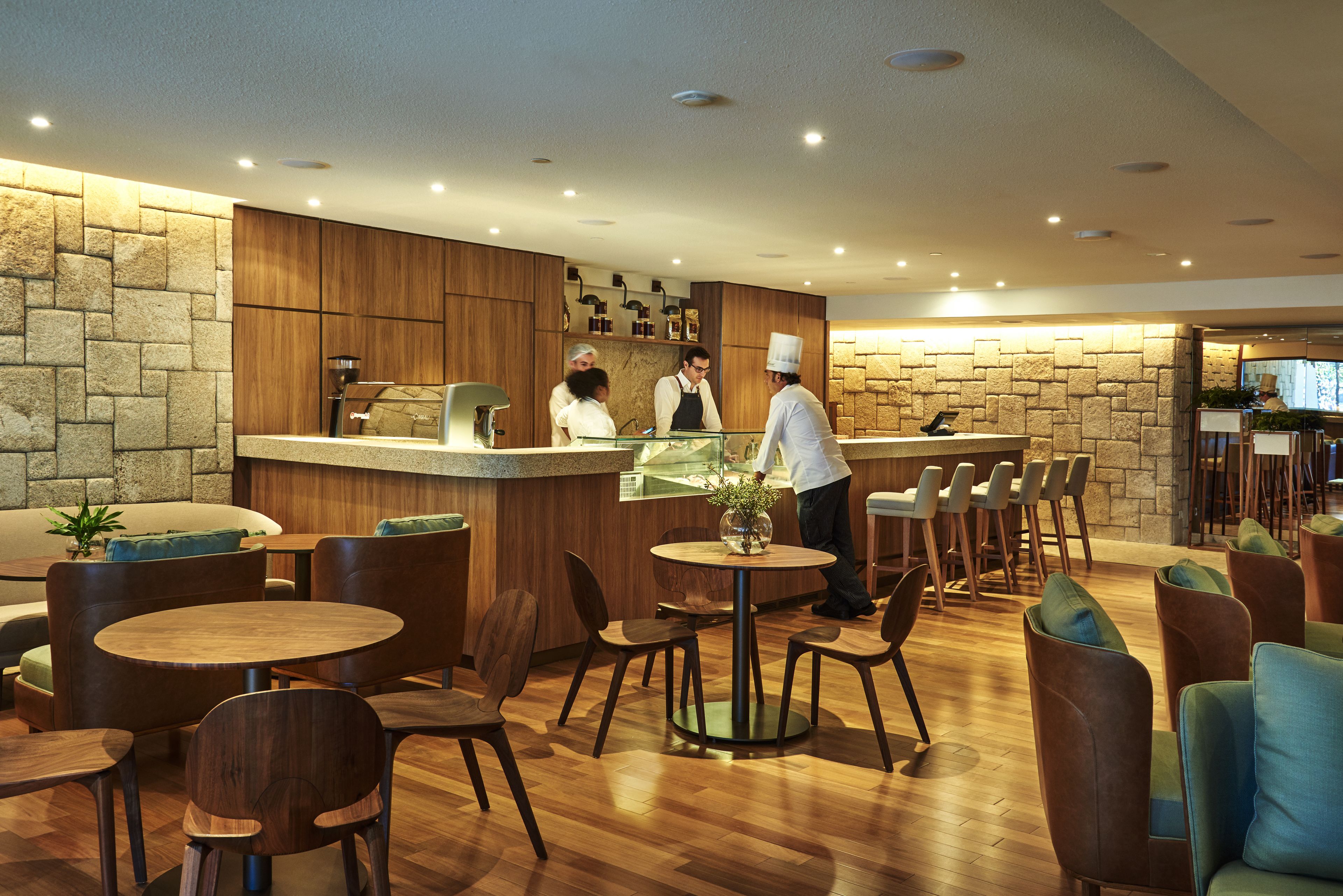 Um restaurante moderno com mobiliário de madeira, parede de pedra e área de bar.