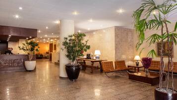 Welcome to our hotel lobby, featuring a reception desk, comfortable seating area, and lush greenery.