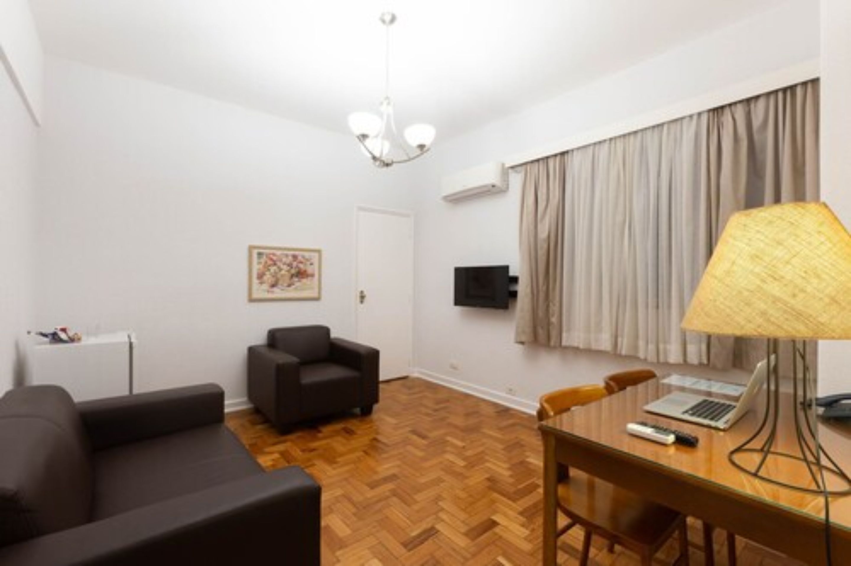 A modern living room with a sofa, a dining table with chairs, a lamp, and a television.