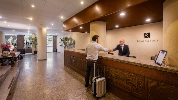 Un mostrador de recepción de hotel con un letrero que dice "ROJAS ALL SUITE".