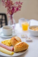 A breakfast setting with a plate of food, a cup, and a glass of orange juice.