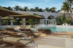 A poolside area with lounge chairs, umbrellas, and a waterfall feature.
