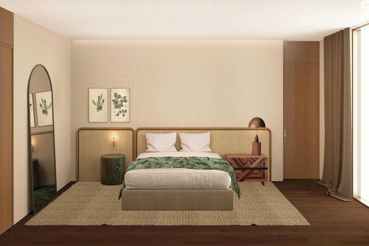 A bedroom with a bed, a mirror, wall art, a bedside table, and a door.