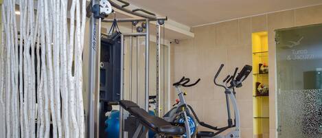 A gym with exercise equipment, a wall with a decorative pattern, and a door with a sign.