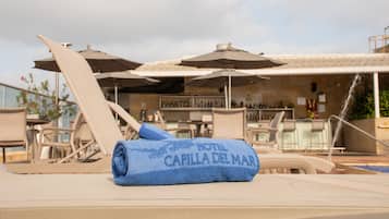 A poolside area with lounge chairs, umbrellas, and a bar.