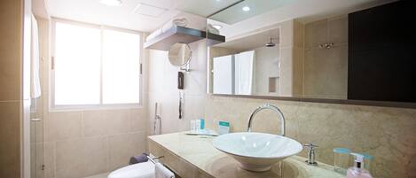 Un baño moderno con un lavamanos grande, espejo y ducha.