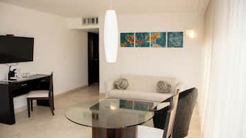 Un salon moderne avec une table à plateau en verre, un canapé, un téléviseur et des œuvres d’art accrochées au mur.