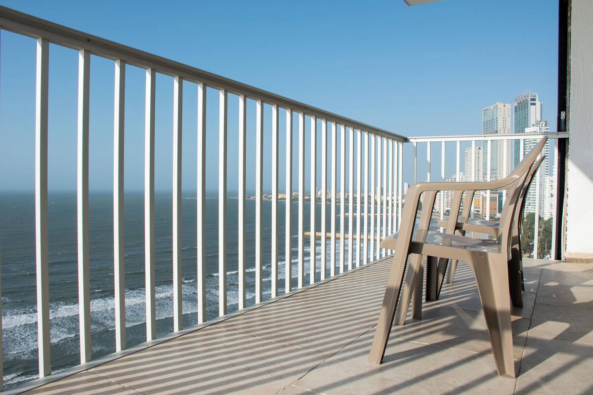 A balcony with a view of the ocean and cityscape.