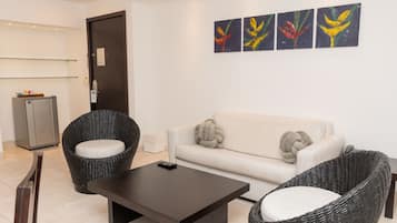 A modern living room with a sofa, two wicker chairs, a coffee table, and a refrigerator.