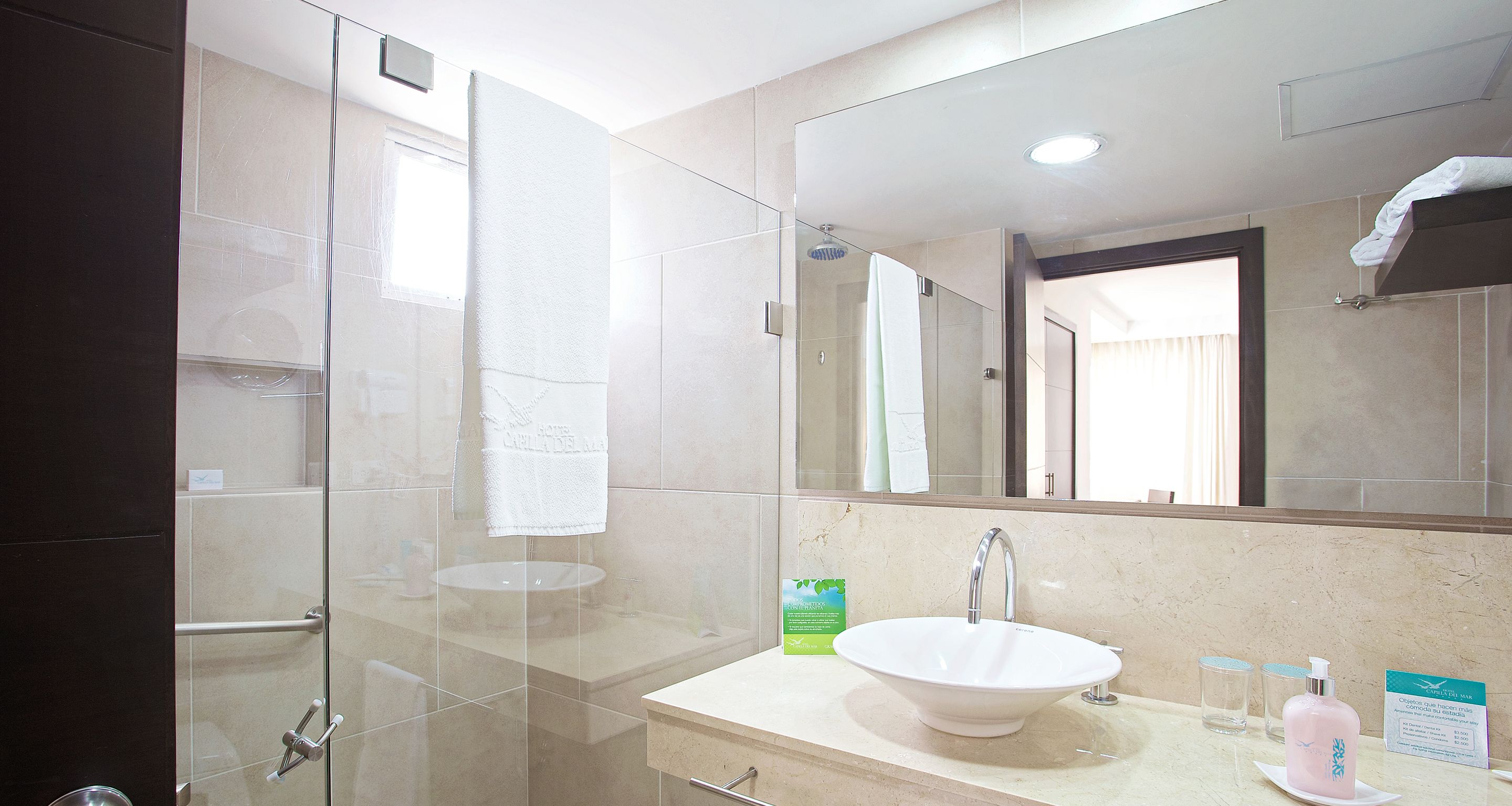 Een moderne badkamer met een douchecabine van glas, een wit wastafelmeubel en een grote spiegel.