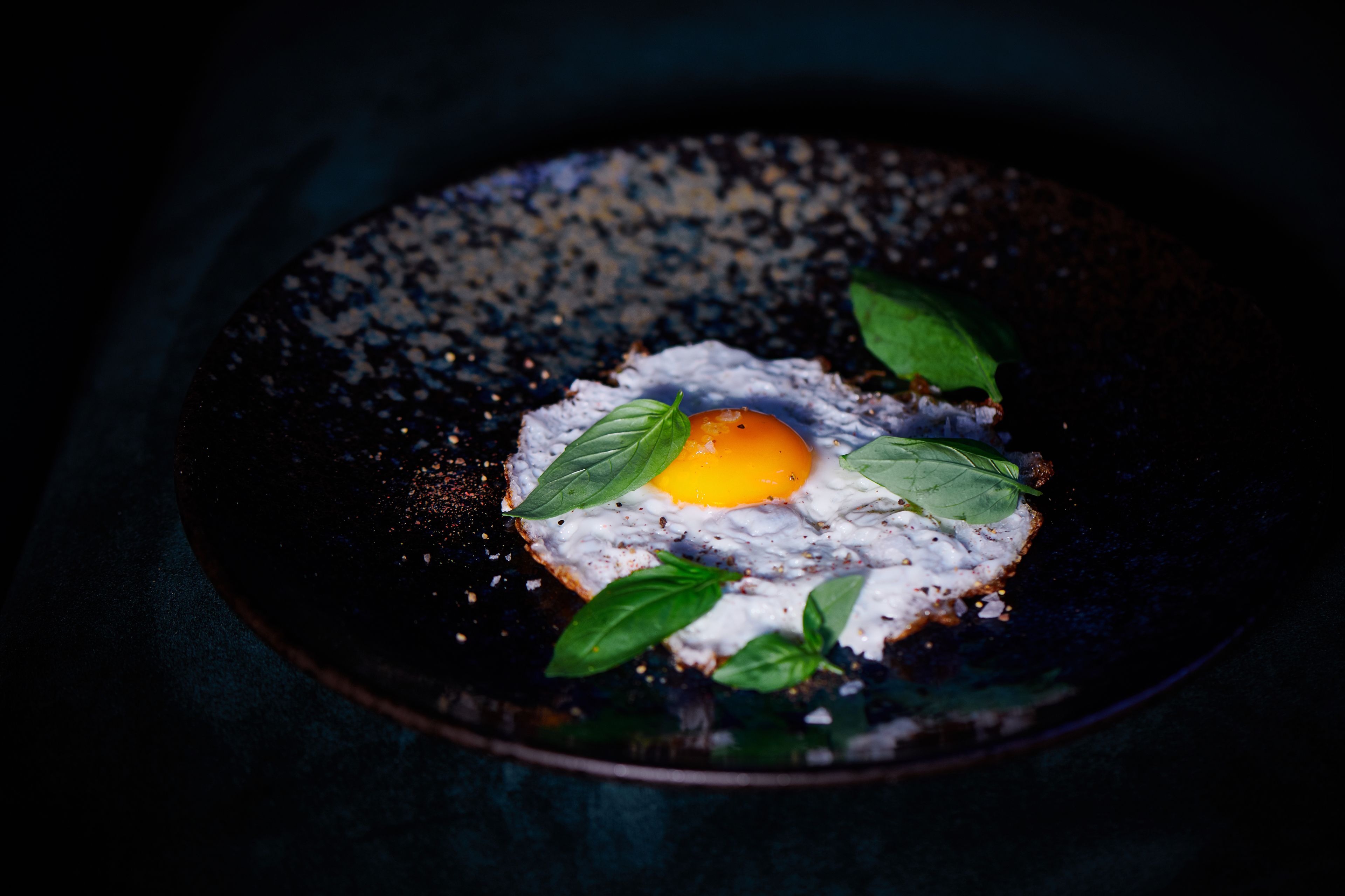 A plate with a fried egg, greens, and a slice of bread.