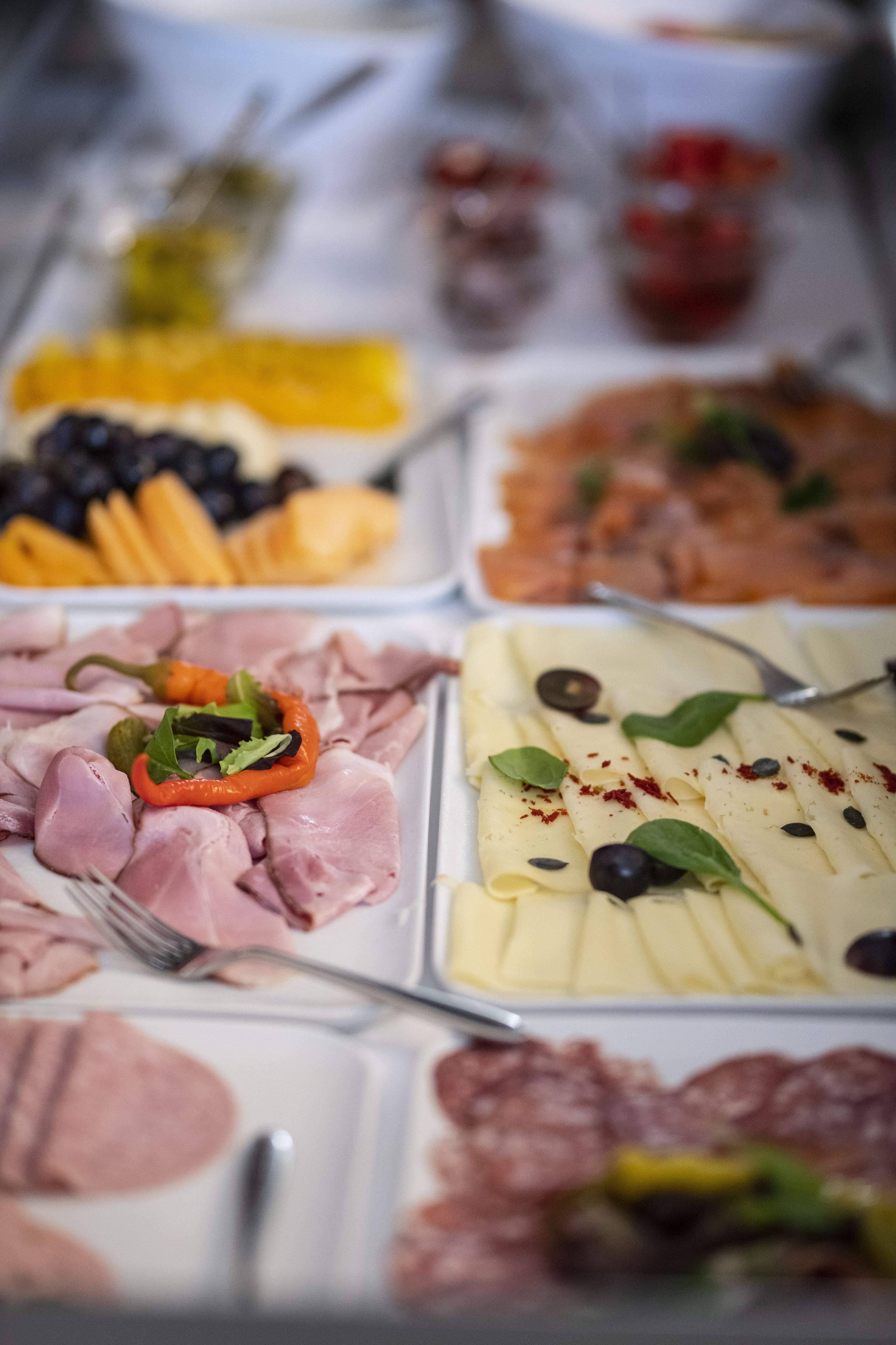 A buffet with various food items including meats, cheeses, and vegetables.