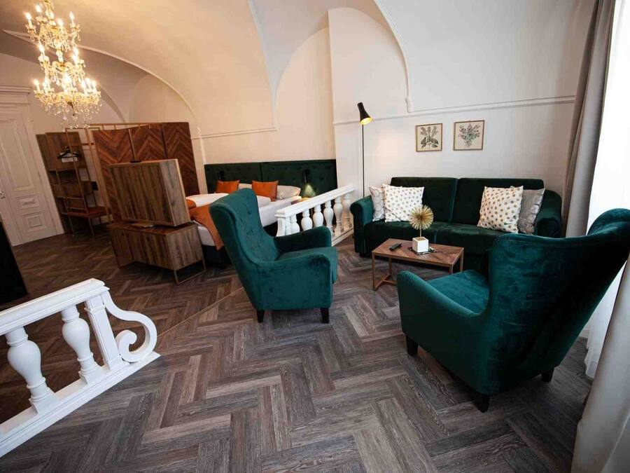 Amplia sala de estar con suelo de espiga, sofá verde, mesa de centro de madera y candelabro.