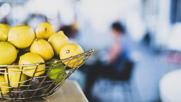 A basket of lemons on a wooden surface.