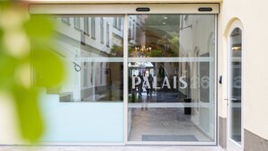 Entrada de hotel con puerta de cristal que muestra el nombre "PALAIOS 26".