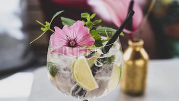 Ein Cocktailglas mit einer rosa Blume, einer Limettenscheibe und Minzblättern.