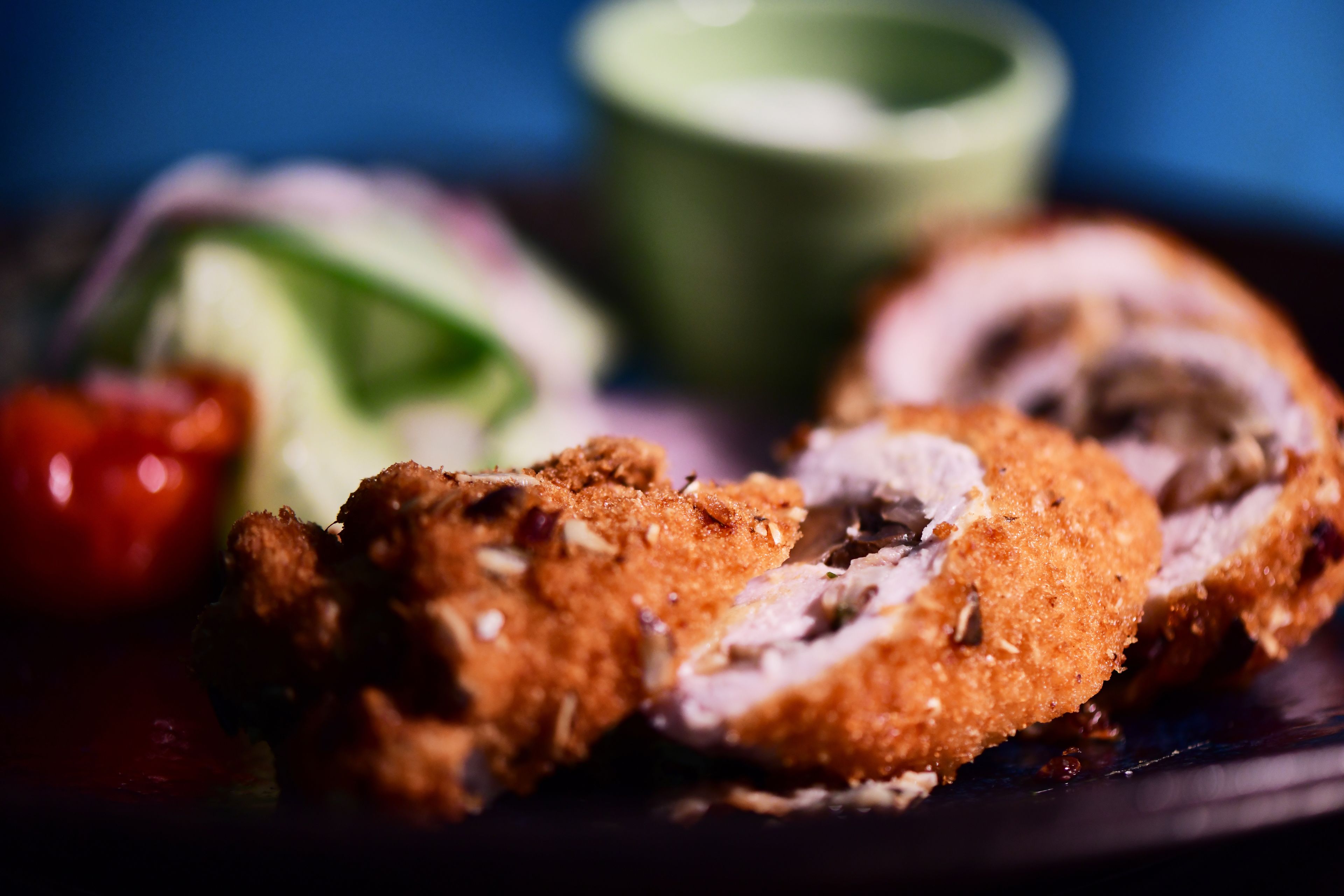 A close-up of a breaded and fried food item, possibly chicken, with a slice cut open to reveal the inside.
