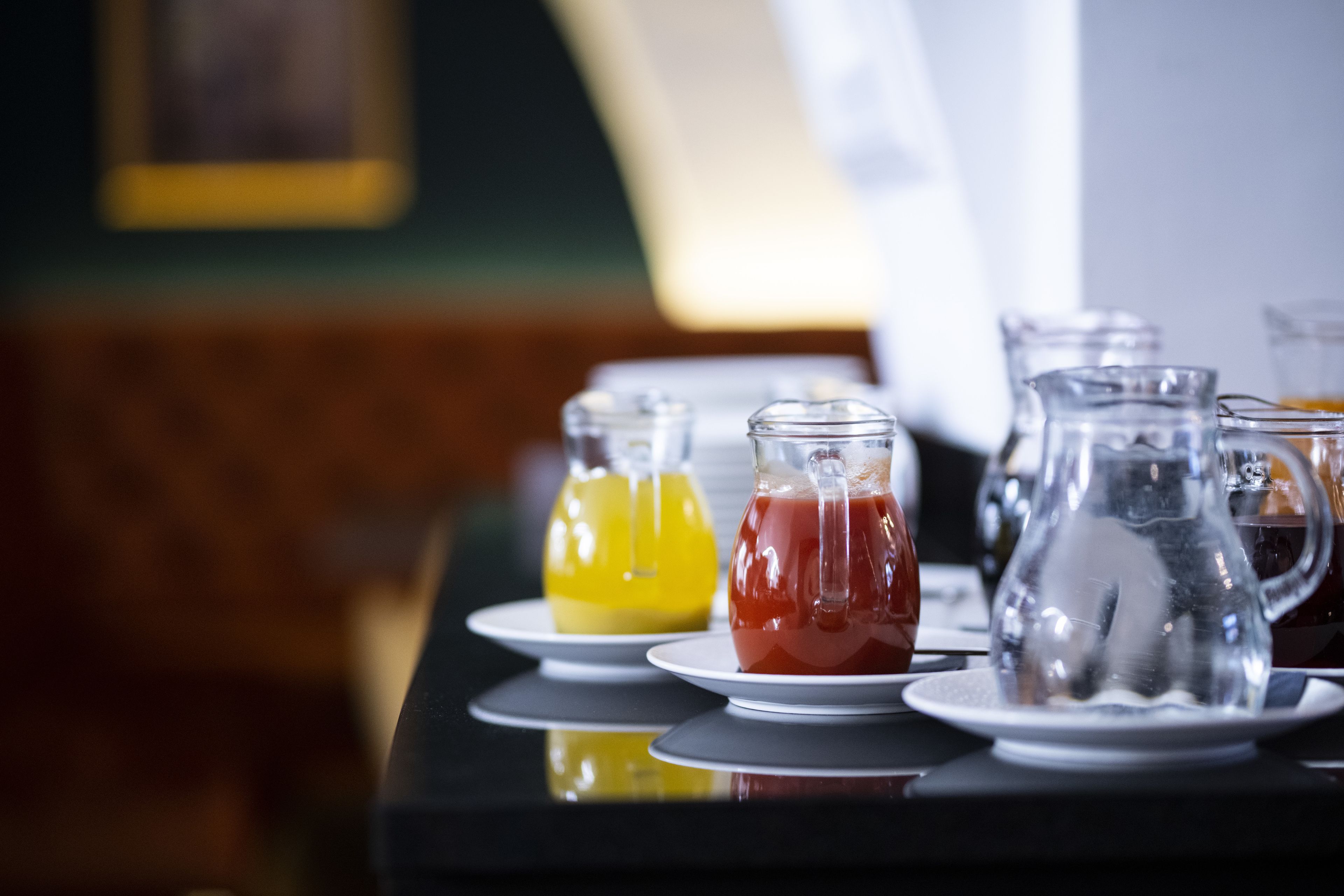 Une table avec différentes boissons servies dans des récipients en verre, présentées sur des assiettes blanches.