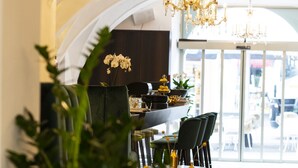 Un comedor moderno con techo alto, candelabros y vista de la calle a través de grandes ventanales.