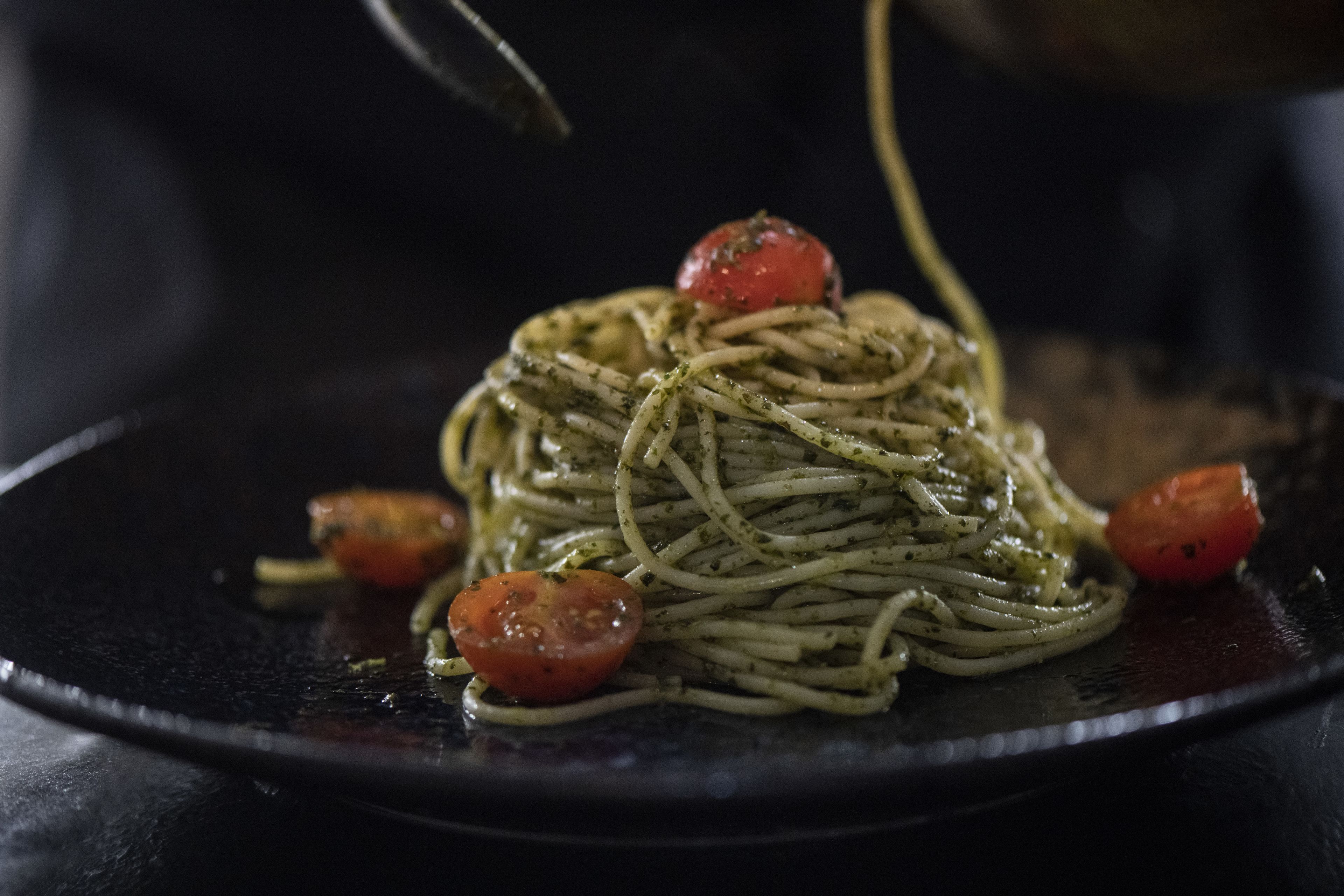 A plate of spaghetti with tomato garnish.