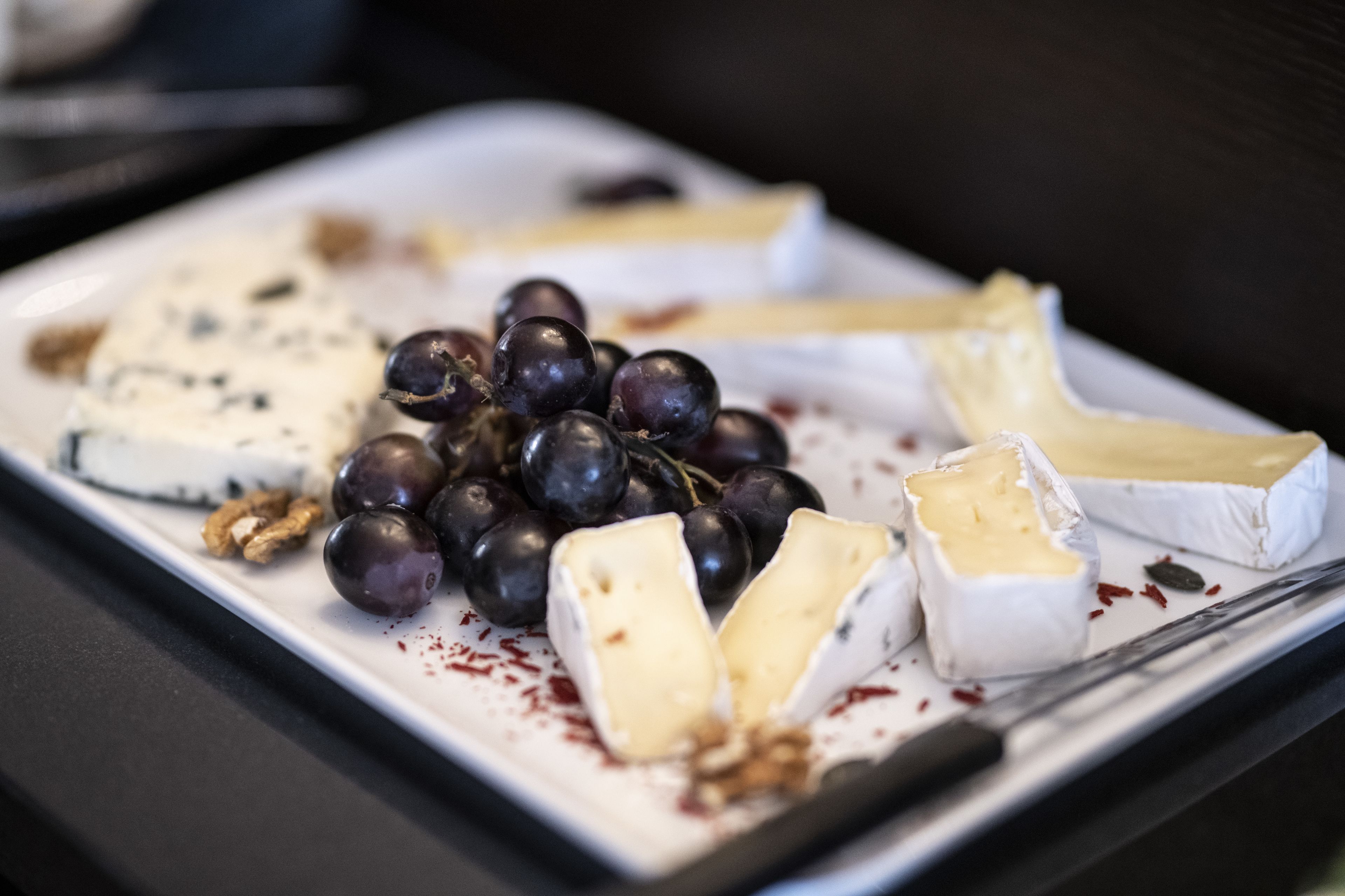A plate of assorted cheeses and grapes.