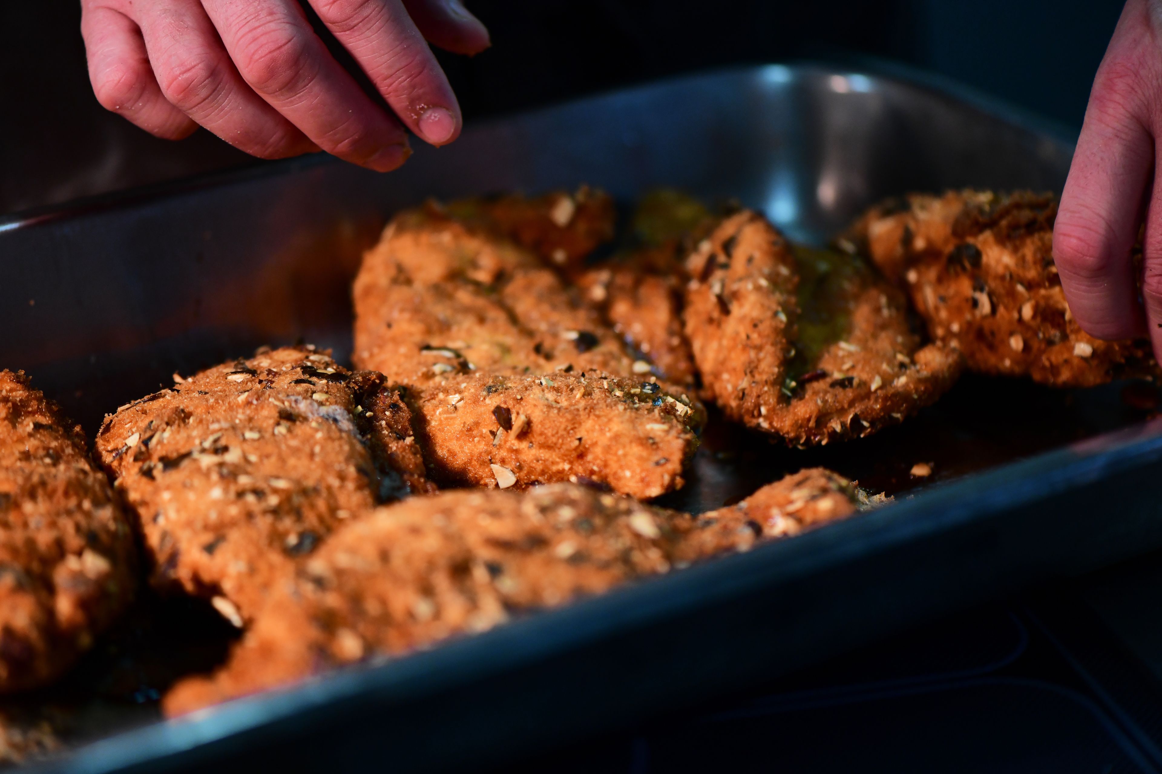 A tray of food items, possibly meatballs, seasoned with herbs and spices.