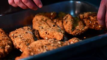 A tray of food items, possibly meatballs, seasoned with herbs and spices.