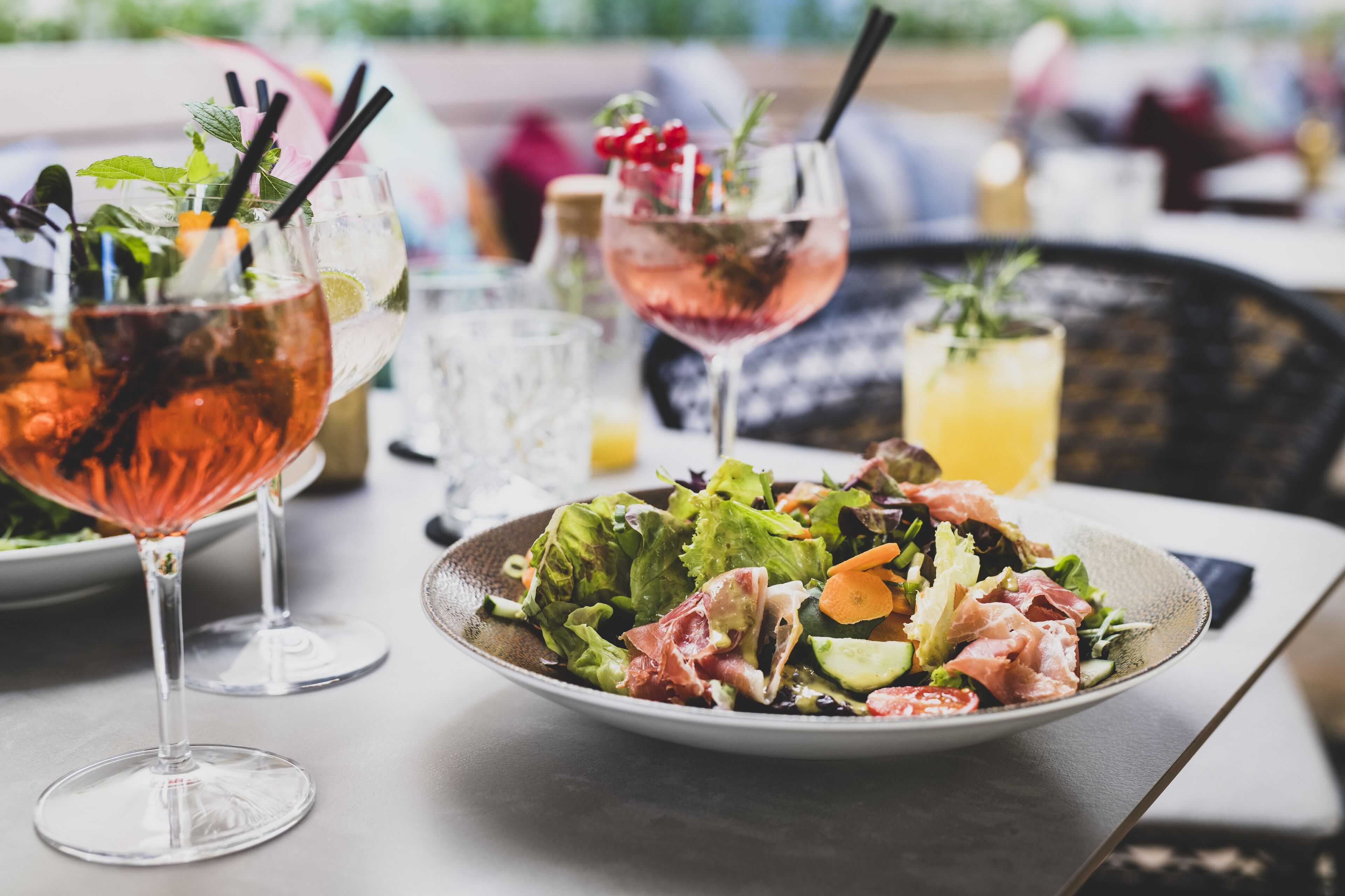 Et bord med to cocktails, en salat og et glas juice.