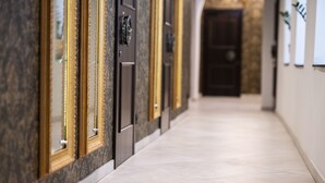 Un pasillo con puertas, piso de baldosas y una pared con textura.