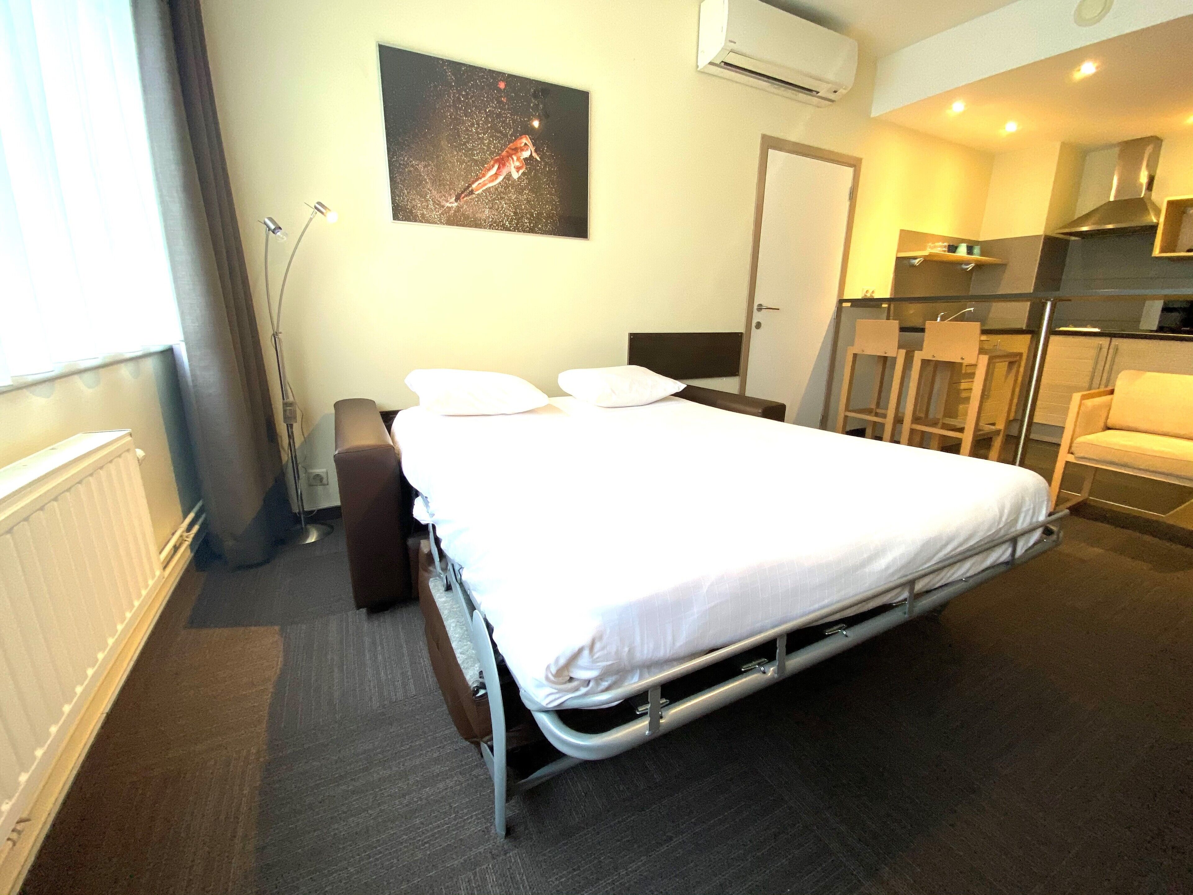 Een hotelkamer met een bed, een bureau, een stoel en een kitchenette.