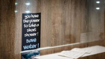 A wooden wall with a sign encouraging to take a short shower to save water.