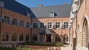 Een binnenplaats met een bakstenen gebouw, voorzien van boogvensters en een open ruimte in het midden.