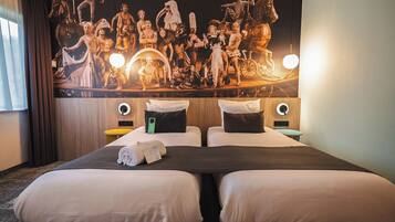 A hotel room with two beds, a large wall mural, and bedside lamps.