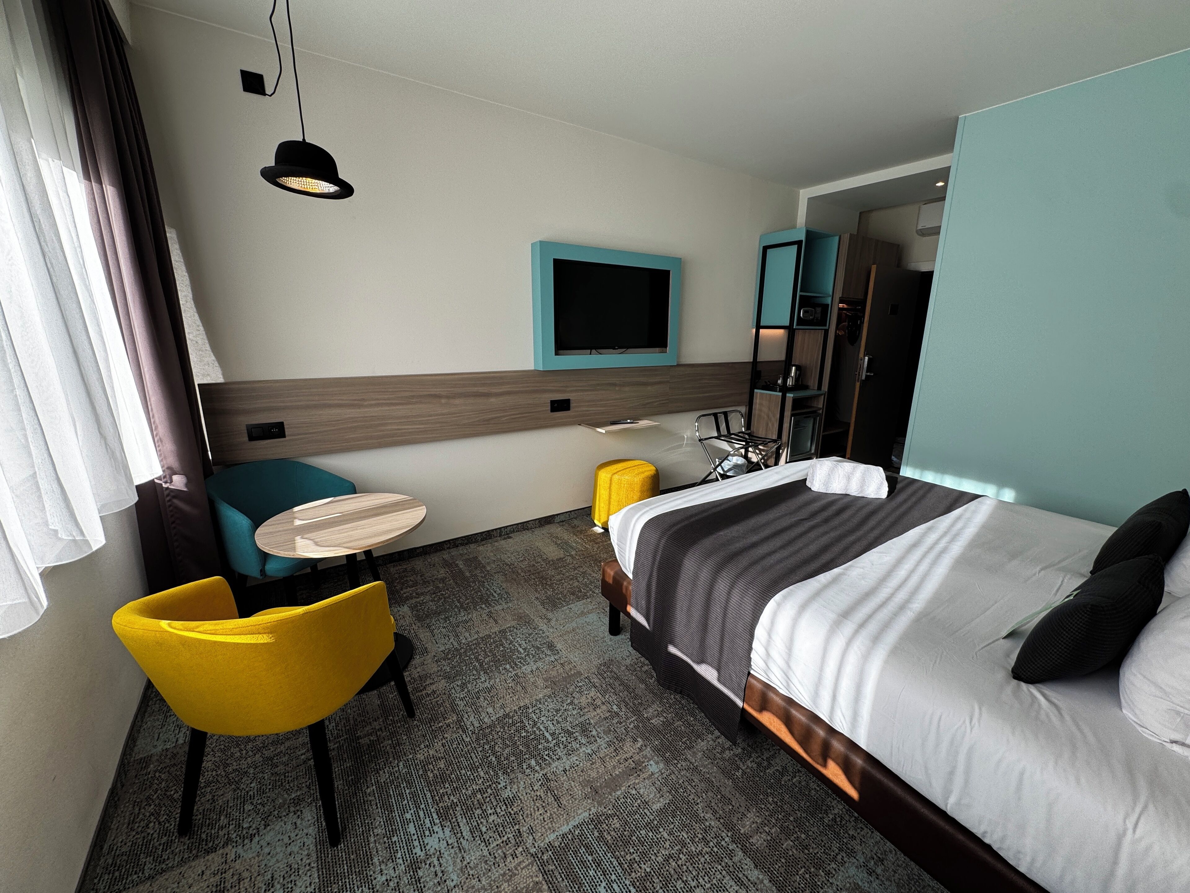 Una habitación de hotel con cama, escritorio, silla, televisor y baño.