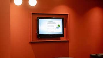 Un salón de conferencias con una pantalla grande mostrando una presentación, una mesa larga y varias sillas.