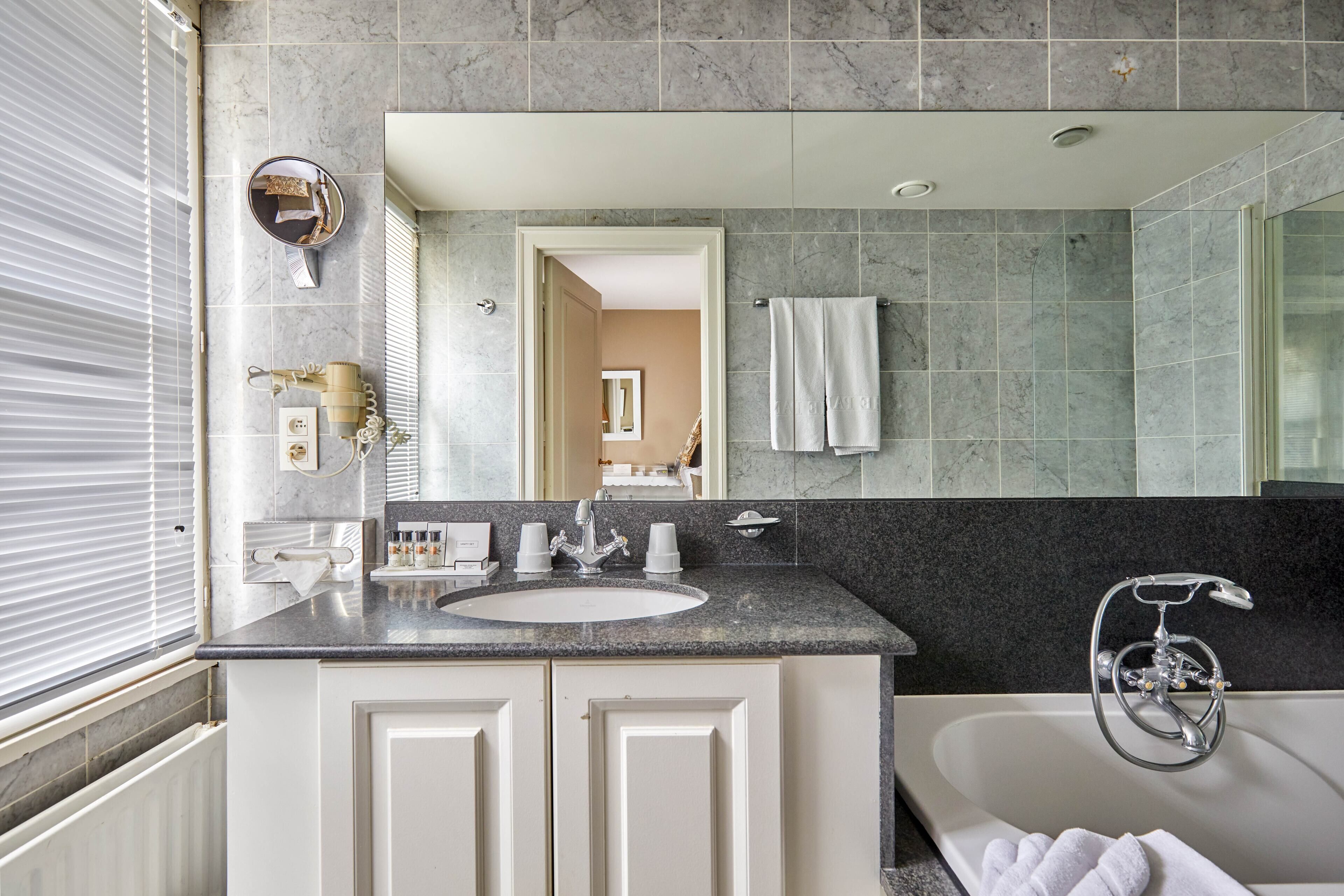 Un baño moderno con un lavamanos grande, espejo y bañera.