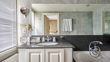 Un baño moderno con un lavamanos grande, espejo y bañera.