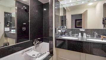 A modern bathroom with a large mirror, two sinks, a bathtub, and a vanity with a mirror.