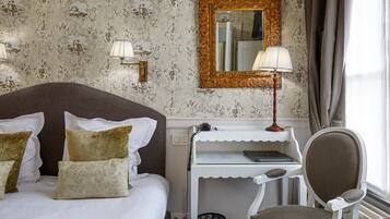 Een hotelkamer met een groot bed, een bureau met lamp, een stoel en een spiegel aan de muur.