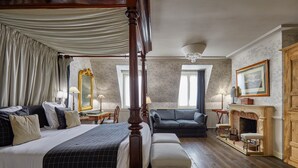 Un dormitorio con cama con dosel, un sofá, una chimenea y un espejo grande.