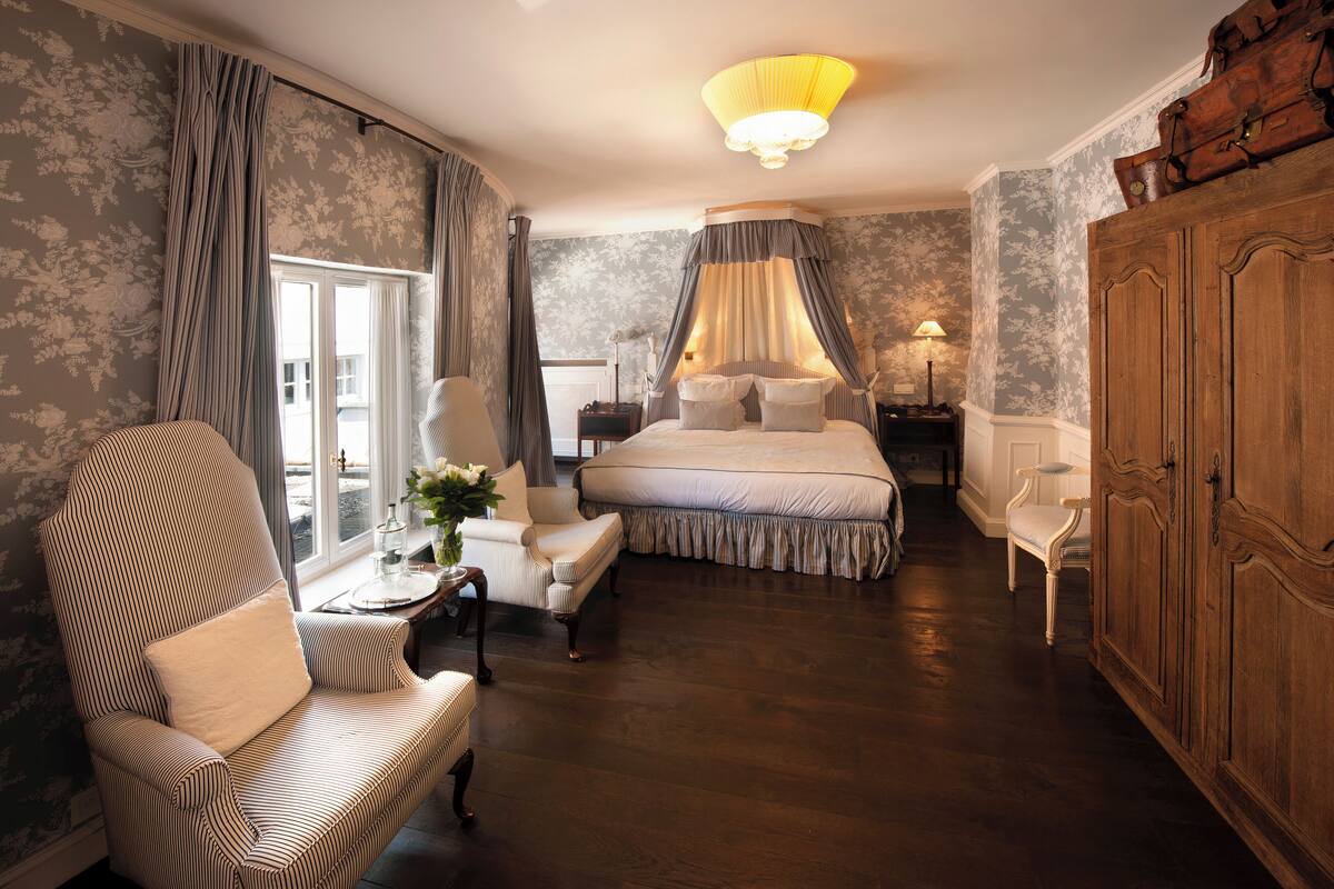 A bedroom with a large bed, a chair, a nightstand, and a wardrobe.