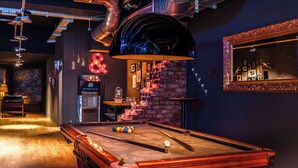 A pool table in a dimly lit room with a brick wall and a neon sign. - pentahotel Liège (Liege)