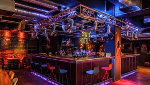 A bar with a wooden counter, bar stools, and a neon sign. - pentahotel Liège (Liege)