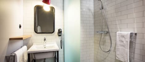 A bathroom with a sink, mirror, red pendant light, and a shower area with a towel rack.