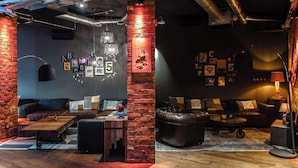 A modern living room with a brick column, leather sofas, a coffee table, and a rug. - pentahotel Liège (Liege)