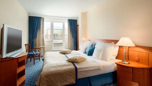 Een hotelkamer met een bed, een televisie, een bureau en een stoel.